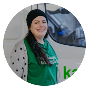 Woman standing in front of a van wearing a black beanie and green t-shirt.
