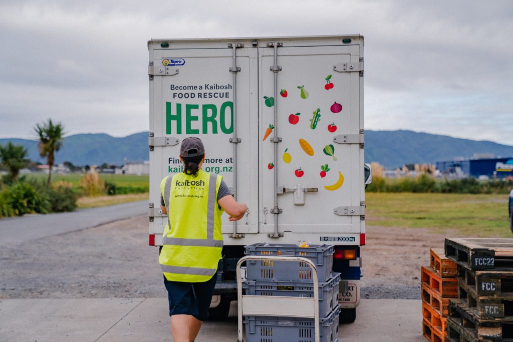 Kaibosh food recue driver opens back of truck in a supermarket carpark.